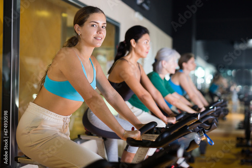 Portrait of young woman training on stationary bike workout in gym