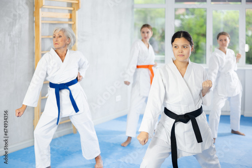 Women of different ages in kimono trying new martial moves at karate class