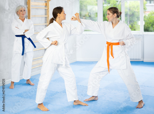 Group of women in kimonos train karate techniques in studio