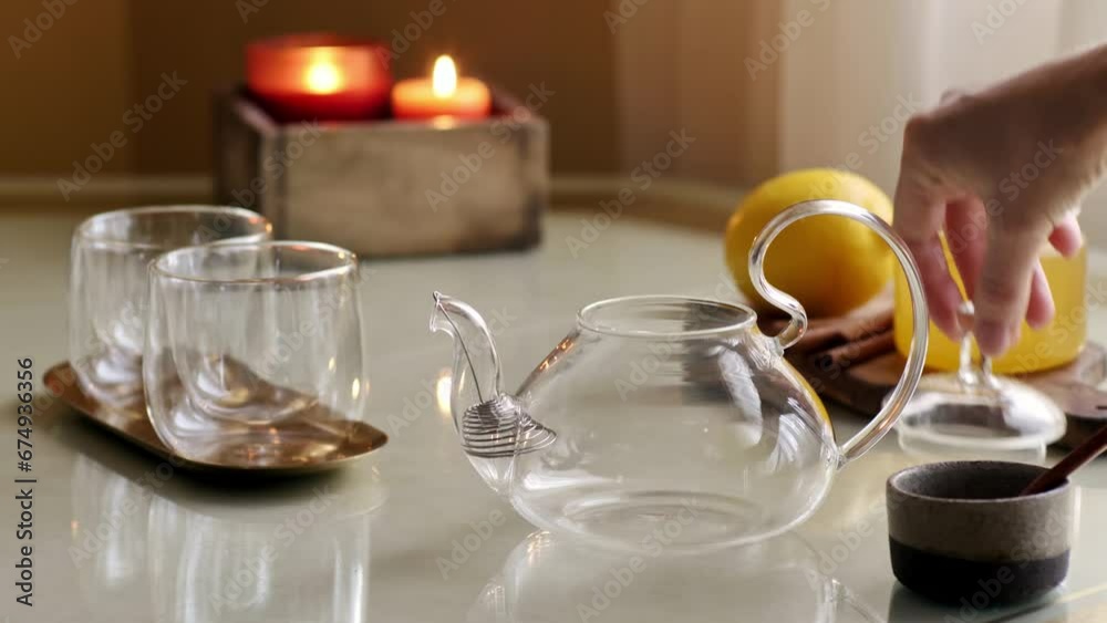 Pouring dry tea leaves into glass teapot on table with cup, honey and lemon. 4k video Pouring dry tea leaves into glass teapot on table with cup, honey and lemon. 4k video
