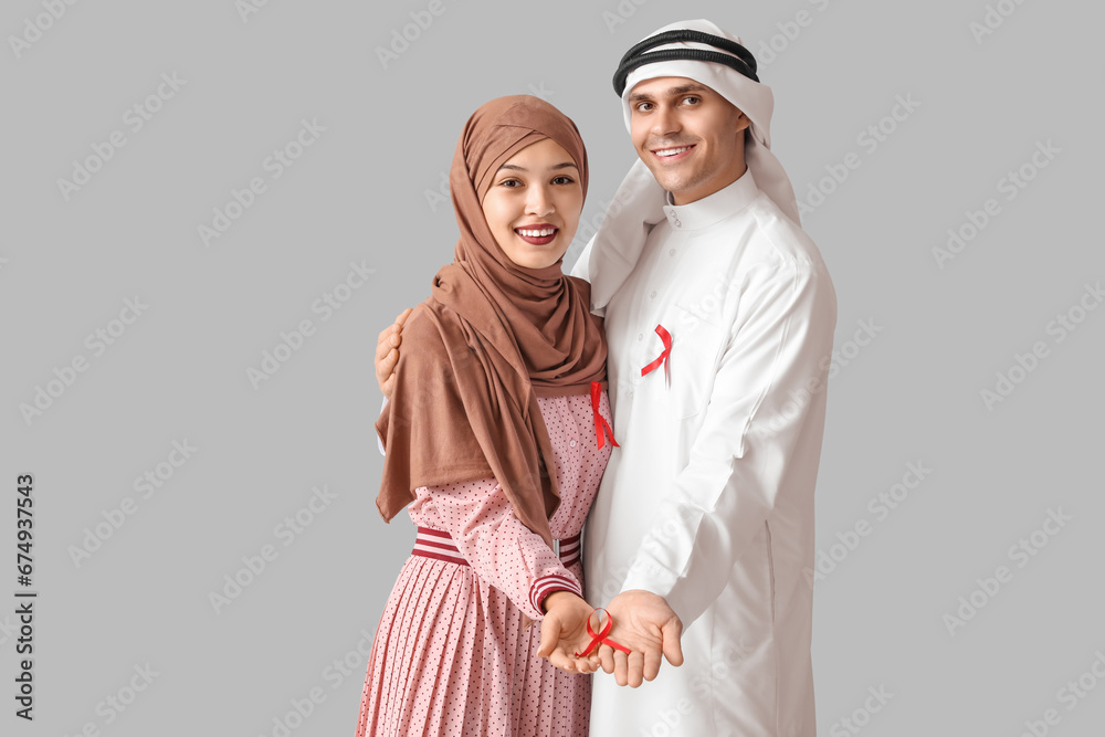 Beautiful Muslim couple with red ribbons on grey background. AID awareness concept Beautiful Muslim couple with red ribbons on grey background. AID awareness concept