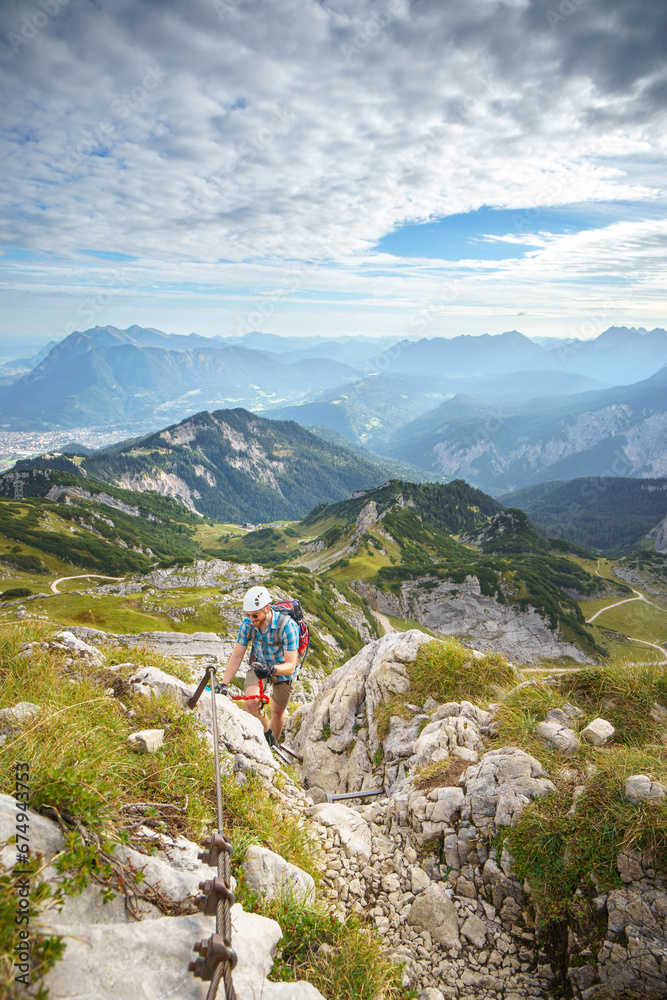 Fototapeta premium Ein Wanderer kletter über einen Klettersteig auf die Alpsitze in den Bayerischen Alpen.