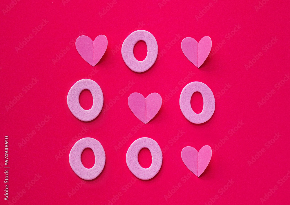 Tic tac toe made of hearts and zeros on pink background. Love always wins concept. Flat lay. Valentine's or love concept.