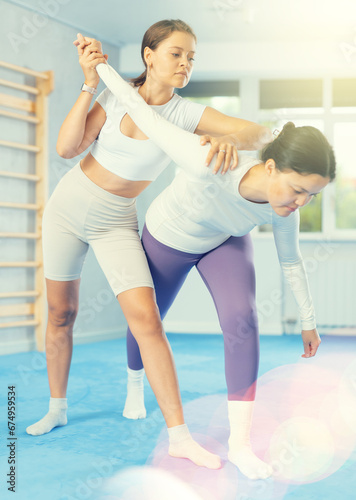 Women exercising armlock grip while sparring in gym