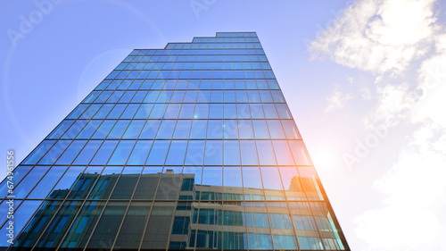 Looking up blue modern office building. The glass windows of building with  aluminum framework.