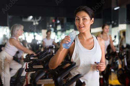 Portrait of asian woman who drinking water during cycling class in modern gym