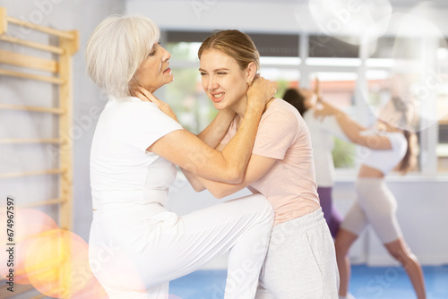 Girl and woman in sparring practice technique of applying painful blows to jaw and groin to neutralize enemy. Class self-defense training in presence of experienced instructor © JackF