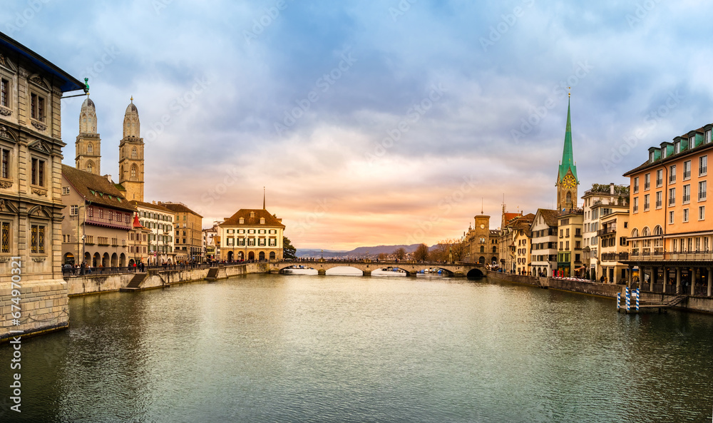 Fototapeta premium Panoramic view of Zurich city center, Switzerland. Zuerich old town with famous Fraumunster and Grossmunster Church on bank of river Limmat at sunset with dramatic sky in winter