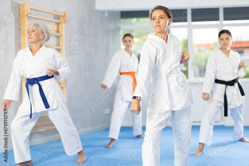 Female students of martial arts academy look at Kata karate teacher conducts classes and performs movements and fighting techniques together