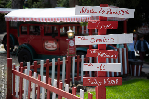 Placas com mensagens de natal e carro do papai noel ao fundo desfocado. photo