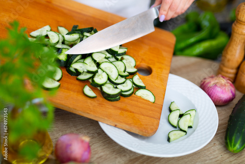 Image of female hands cut fresh cucumbers for vegetable salad, nobody