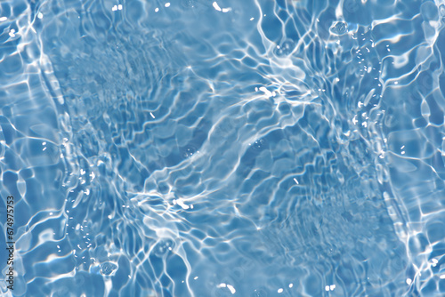 Fototapeta Naklejka Na Ścianę i Meble -  Defocus blurred transparent blue colored clear calm water surface texture with splashes reflection. Trendy abstract nature background. Water waves in sunlight with copy space. Blue watercolor shine.