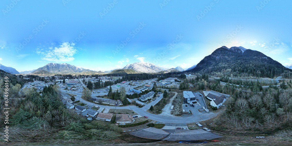 Aerial view of a village between the mountains and trees with cars parked in front of the buildings