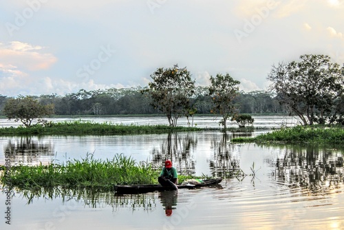 Man canoeing in a tranquil lake surrounded by lush vegetation