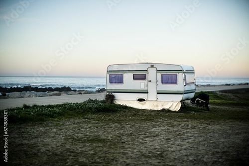 a trailer parked on the shore next to a beach with the ocean in the background