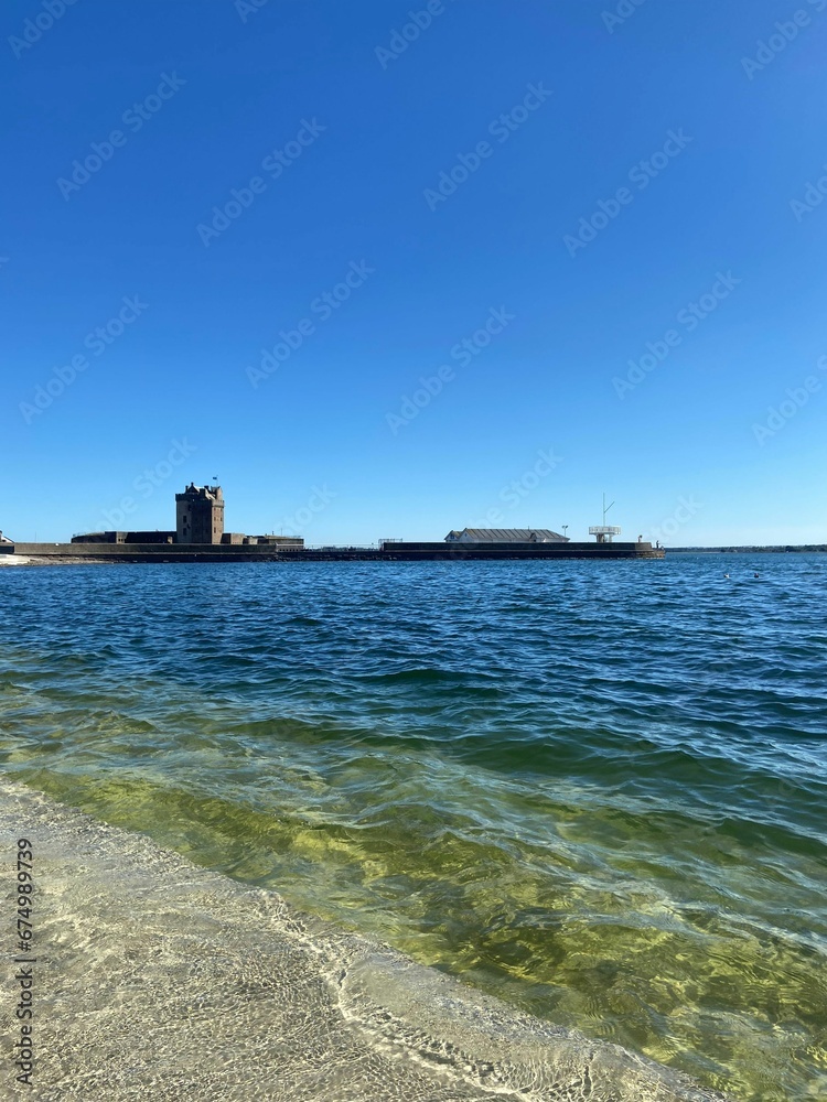 Serene shoreline of a tranquil sea with buildings in the background