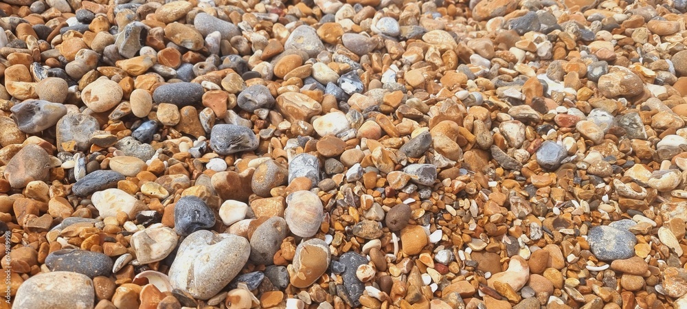 Close-up shot of a beach shoreline featuring a variety of small pebbles and rocks Close-up shot of a beach shoreline featuring a variety of small pebbles and rocks