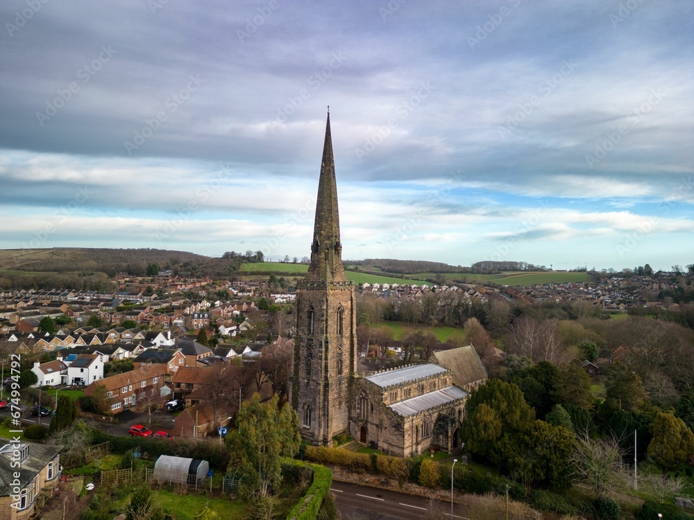Picturesque view of an old church with a steepled roof, surrounded by a partly cloudy sky in Gedling
