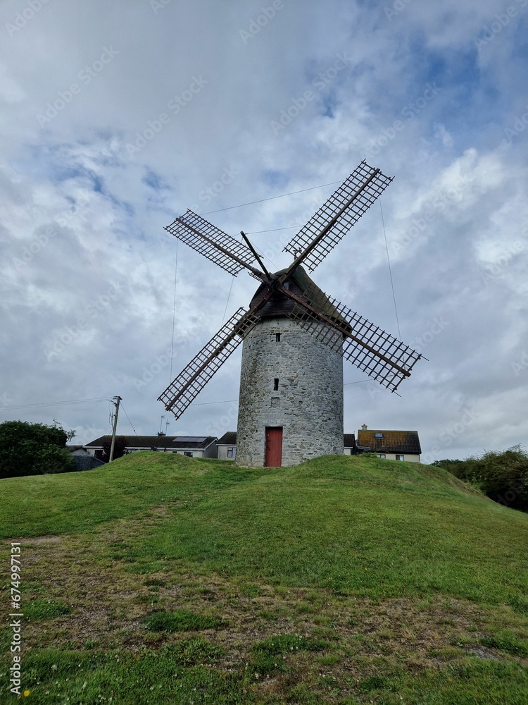 Large windmill stands tall against a bright blue sky in a peaceful, green field in Skerries