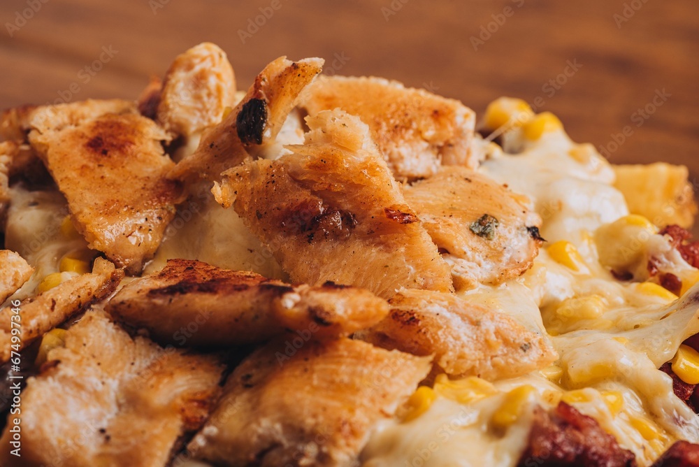 Closeup shot of a dish with french fries, sausages topped with cheese and corn on a wooden table. Closeup shot of a dish with french fries, sausages topped with cheese and corn on a wooden table.