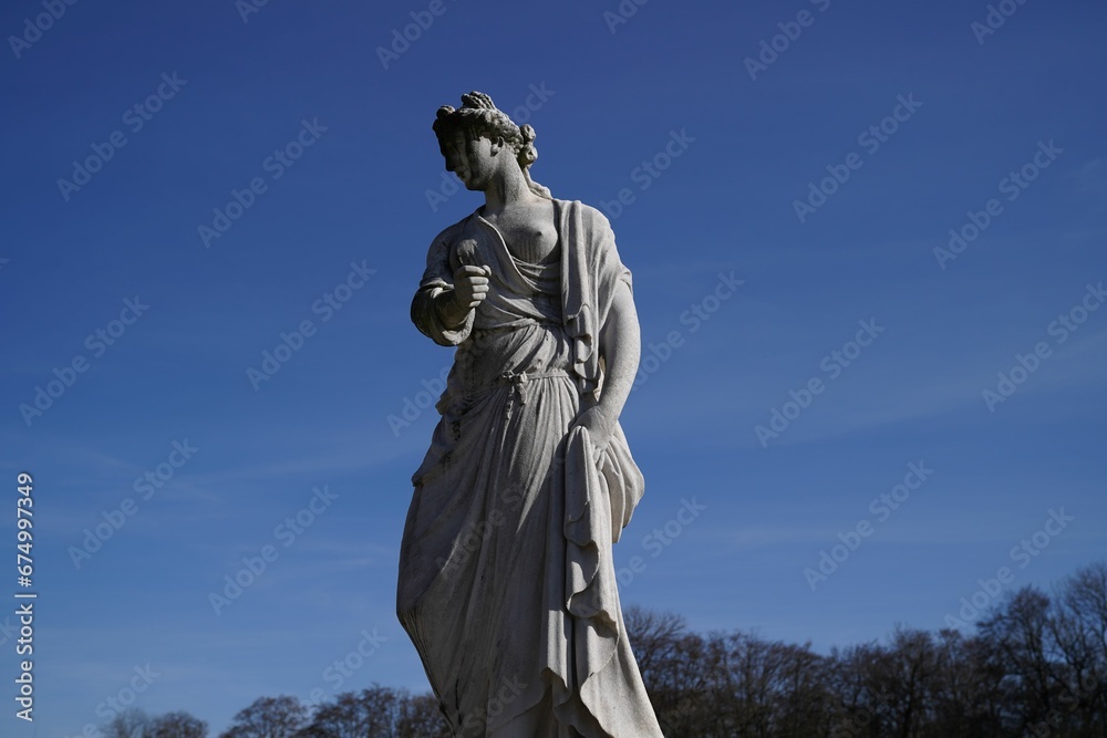 Vibrant outdoor scene of a female statue standing against a bright blue sky on a sunny day
