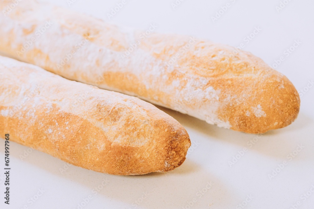 Freshly-baked bread resting on a white table top, with a light dusting of flour