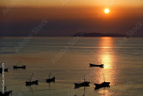 Aerial view of boats sailing in a tranquil sea at sunset