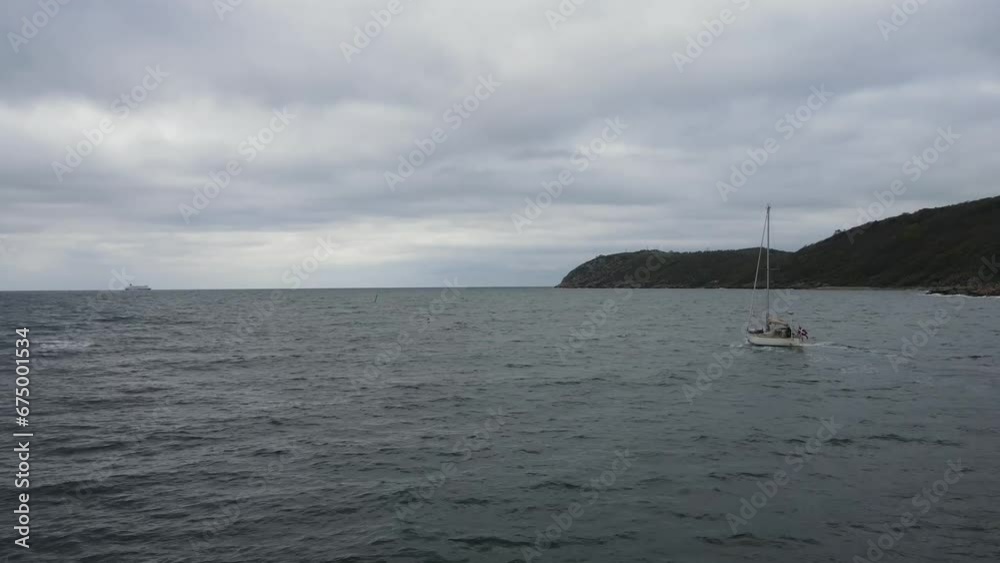 Drone view of a sailboat going out driving in a stormy sea Drone view of a sailboat going out driving in a stormy sea