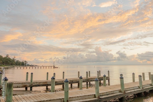 Closeup of a wooden dock stretching over a body of tranquil water at sunset in Fairhope