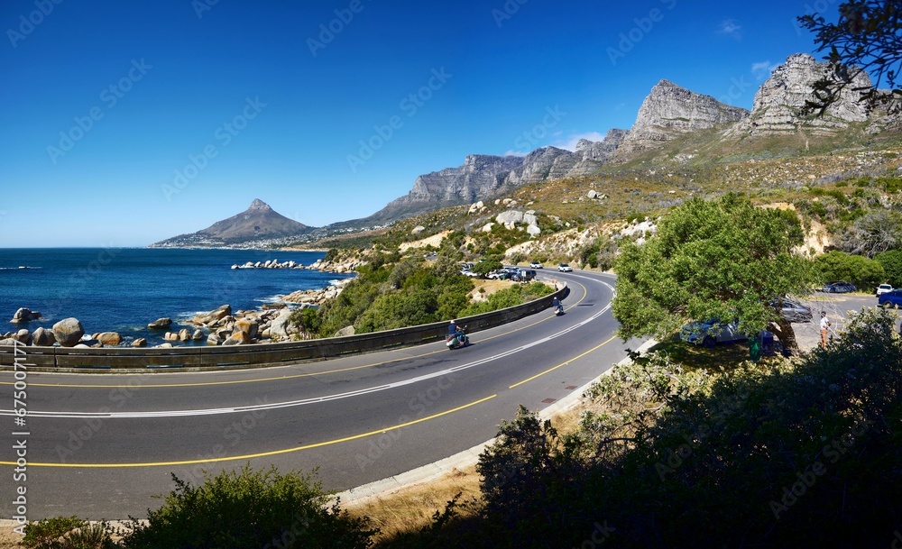 Naklejka premium Curvy road surrounded by mountains. Lionshead and the Atlantic Ocean in Cape Town, South Africa.