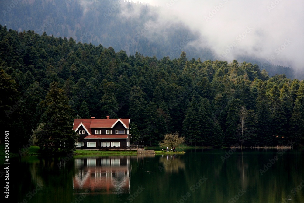 Idyllic house with a red roof on the edge of a tranquil lake, providing a picturesque view