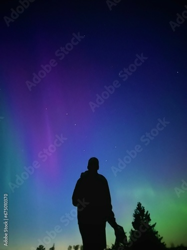 Silhouette of a male in awe, against a backdrop of a beautiful, vibrant aurora in the night sky
