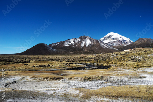 Landscape in sajama national park composed of mountains with snow in the background and Sajama Volcano next to it