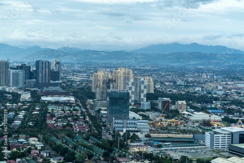 Aerial view of a city skyline features tall buildings and majestic mountain ranges
