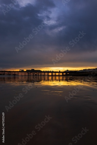 Scenic view of the sun rising over a pier jutting into a body of water © Wirestock