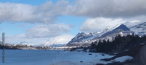 Scenic winter mountain range visible in the distance, blanketed in snow with a tranquil lake