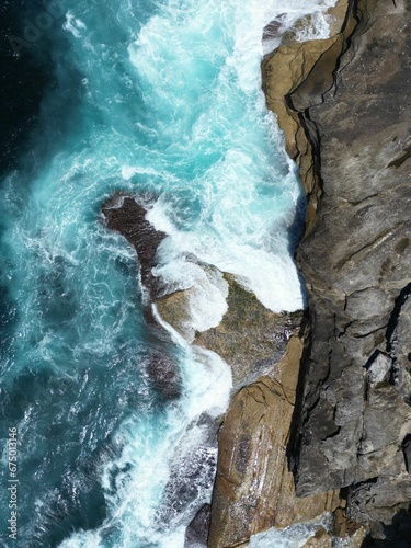 Aerial view of sea waves crashing against the rocky shoreline