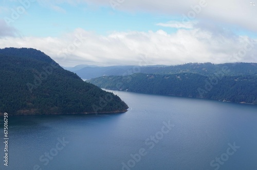 Tranquil landscape of rolling green hills and pine trees surrounding a vast lake