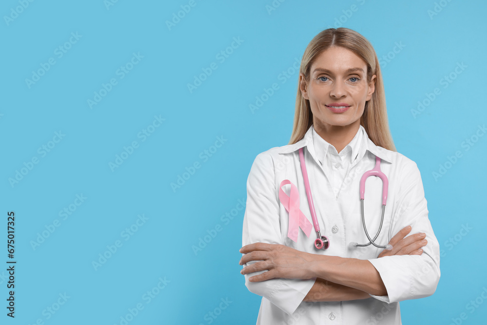 Doctor with pink ribbon and stethoscope on light blue background, space for text. Breast cancer awareness Doctor with pink ribbon and stethoscope on light blue background, space for text. Breast cancer awareness