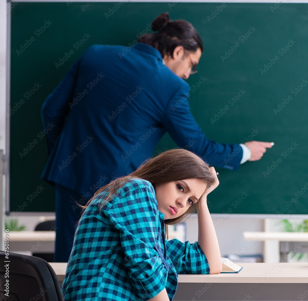 Young handsome teacher and female student in the classroom Young handsome teacher and female student in the classroom