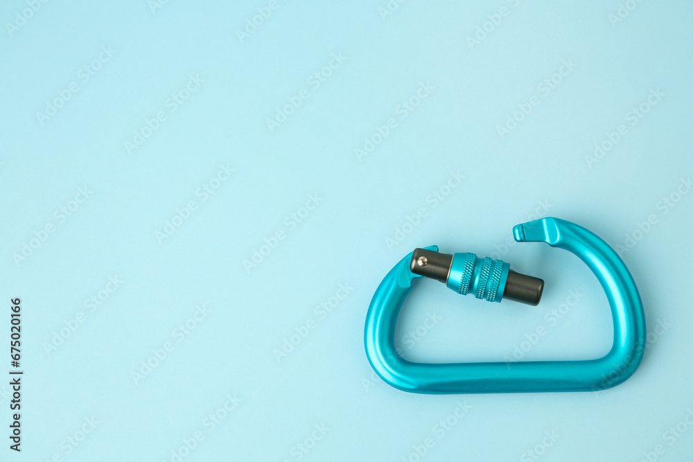 Fototapeta premium One carabiner on light blue background, top view. Space for text