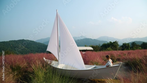 Pretty Girl Playing in Wooden Sail Boat Pretend Being Sailor at Pink Muhly Grass Field - Herb Island Farm in Pocheon - eco tourism in South Korea photo