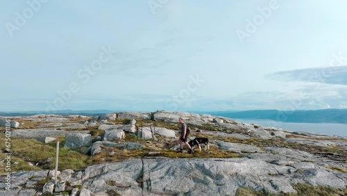 Man And Pet Dog On A Hike At Mountain Blaheia In Nordland, Norway. wide photo