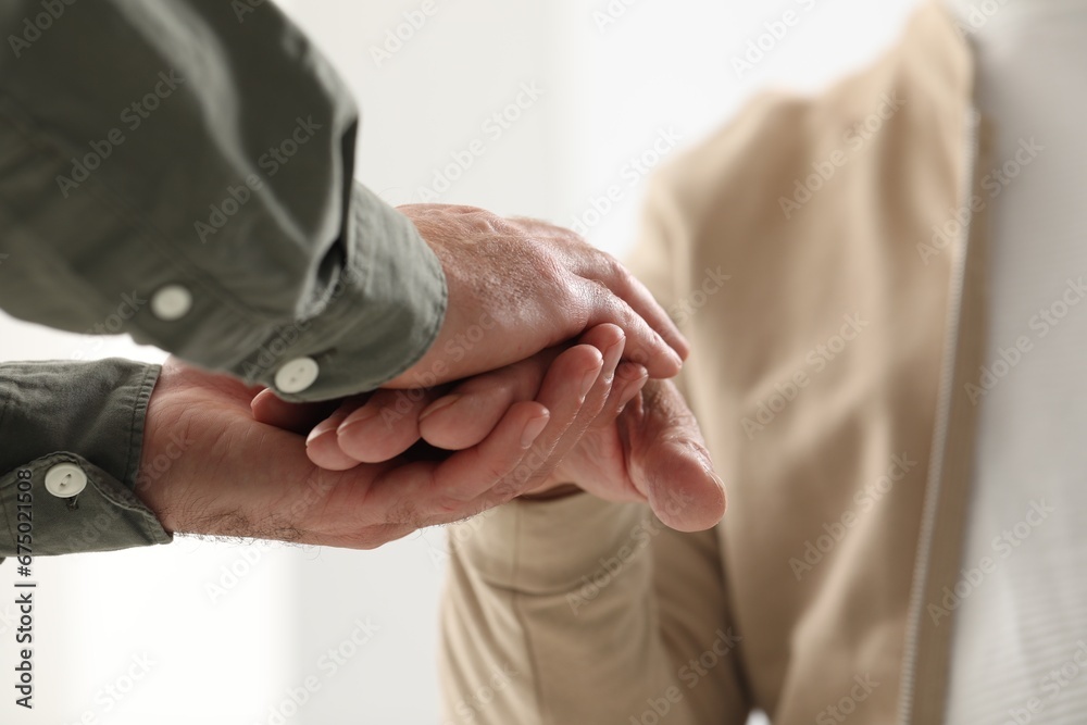 Trust and support. Men joining hands on blurred background, closeup
