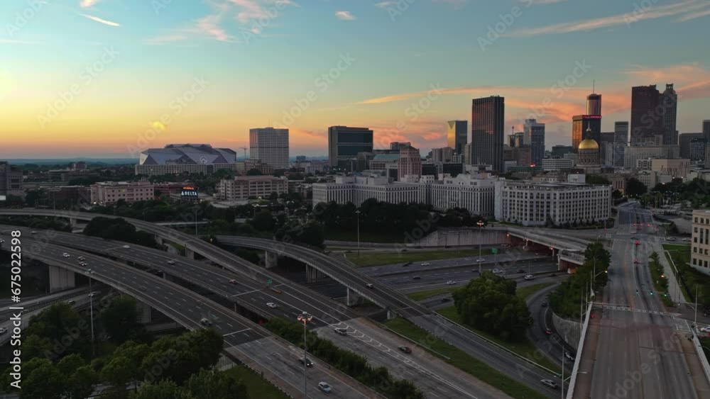 Hyperlapse drone shot of high-frequented highway and lighting Modern Skyline of Atlanta City in background during golden Sunset - Panning drone shot