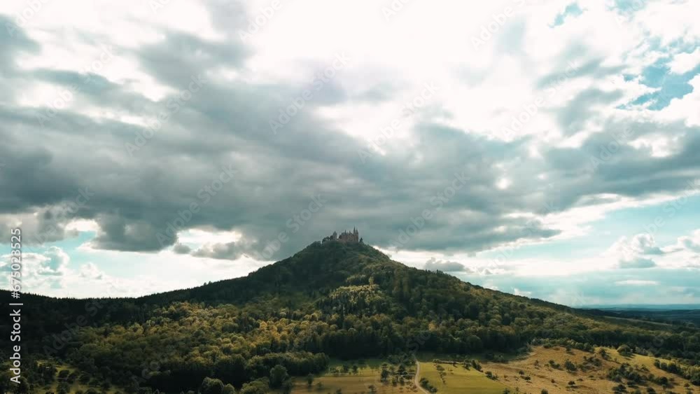 Drone view tilting up of the Hohenzollern Castle atop Hohenzollern Mountain during daylight and the beautiful countryside in Zollernalbkreis, Germany.
