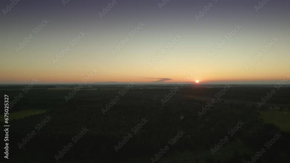 Aerial of a wide green forest with the sunset and the horizon in the background Aerial of a wide green forest with the sunset and the horizon in the background