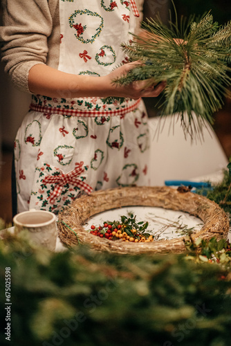 Young woman making Christmas Wreath by herself closeup. Family gathering and crafting handmade decorations from leftover branches, eco concept of reusing and sustainability.