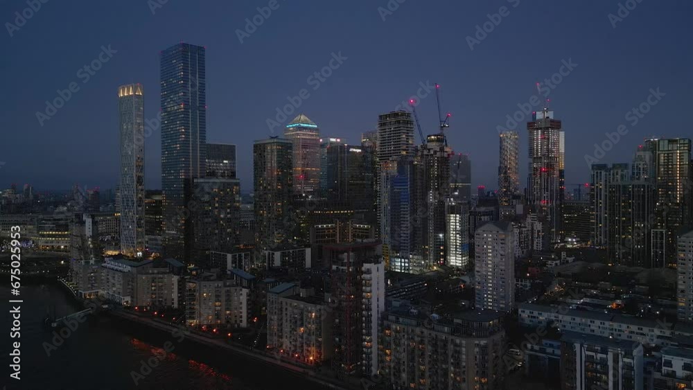 Aerial over River Thames of illuminated Canary Wharf buildings at twilight Aerial over River Thames of illuminated Canary Wharf buildings at twilight