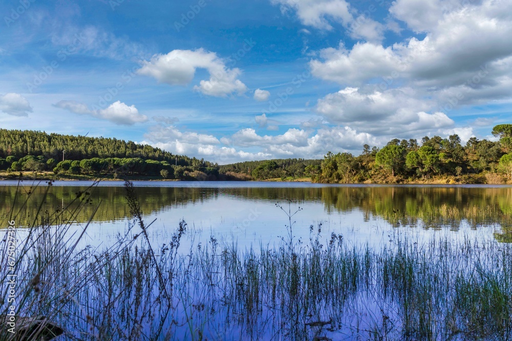 Obraz premium Lake in the woods with beautiful winter blue skies reflections. Bricks water dam in a small village